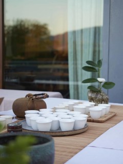 Elegant tea service served on table in front of window terracotta teapot, tray of white bowls on