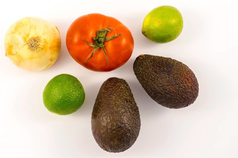 Two good avocados, two limes, an onion, and a tomato. Recipe to make a nice guacamole