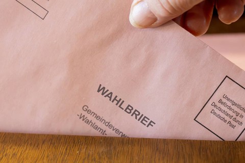 Absentee voting symbol: A ballot letter is thrown into the ballot box of a municipal administration