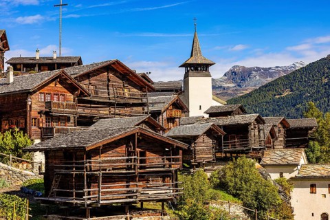 Old wooden houses and the Saint Theodule church in the historic village centre, Grimentz, Val