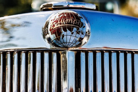 Chrome globe mascot bearing the Triumph name on a vintage car radiator grille