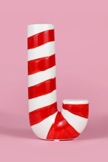 Ceramic red and white striped Christmas candy cane on pink background