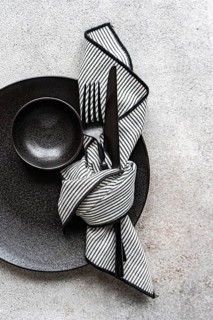 A minimalist black and white table setting featuring a sleek black plate, bowl, and cutlery,