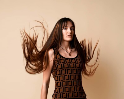 A young woman with face piercing and long flowing hair looking at camera captured in mid motion on