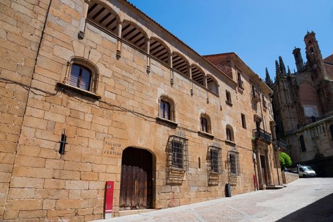 A historic building with stone walls and architectural details under a clear sky, Palacio de