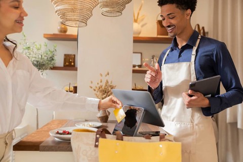 A customer makes a payment using a card at a chic bag store, assisted by a smiling sales assistant.