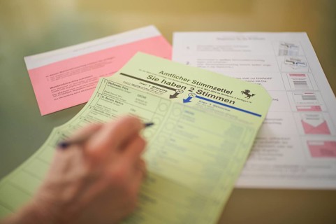 Voting, woman holding ballpoint pen, fills out ballot papers, votes, absentee ballot, official