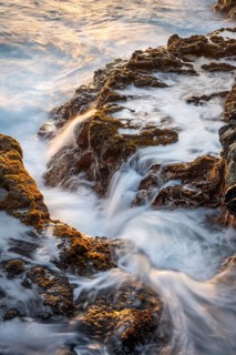 Seawater flows over lava rocks in the morning light. long exposure. Coast near Charco Azul, La