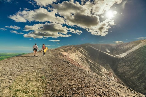 View of two people walking at the top of a volcano. Scene of tourists walking at the summit of the