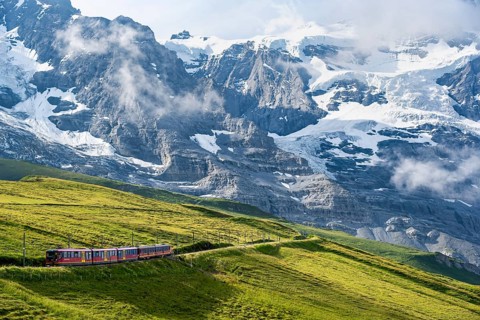 Jungfrau Railway to Jungfraujoch runs through green meadows, above the Kleine Scheidegg stop, rack