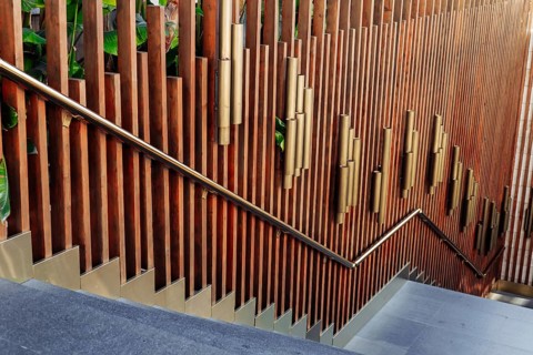 A beautifully crafted wooden stairway features vertical wooden slats and golden accents, surrounded