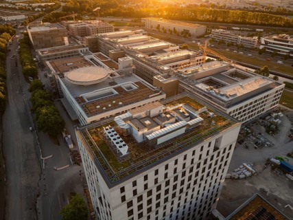 Large building complex at sunset with green roofs and urban surroundings, construction site of the