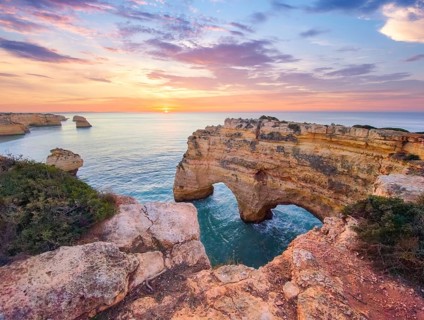 Sunrise at Praia da Marinha beach in Algarve, Portugal, with ocean cliffs, sea stacks and soft