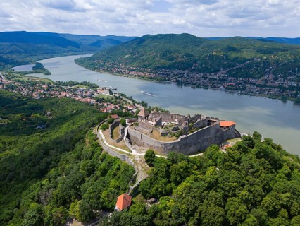 Historic castle with view of a wide river and picturesque green landscape, aerial view, Upper