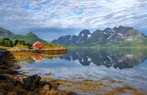 Red fishing hut on the shore, Rorbuer hut, picturesque fjord landscape at Raftsund fjord, mountains