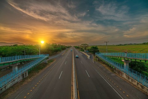Aerial view of a road at sunset with vehicular traffic. Sunset landscape featuring urban traffic
