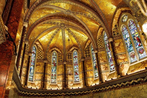 Gilded mosaic vaulting and stained glass windows illuminate the apse of the Grade II listed