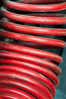 Close-up of large red coiled heavy duty hose of air compressor machine in home garage workshop,