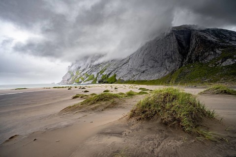 Sand dunes on sandy beaches Bunesstranden between rocky mountain peaks and dramatic clouds,