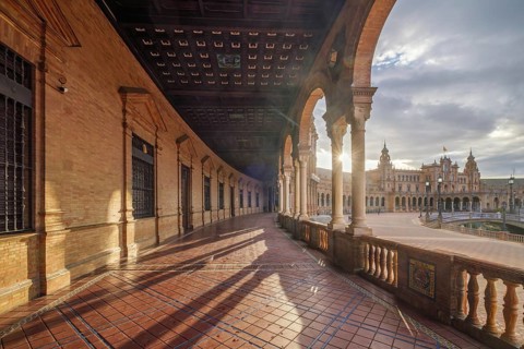 Morning sunstar streams through the arched gallery at Plaza de Espana square in Seville, Spain,