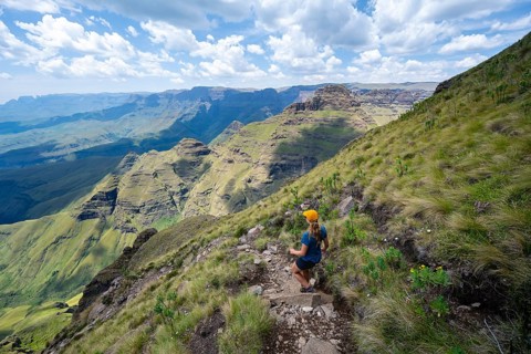 Female mountaineer hiking trail to Cathedral Peak or Cathedralpiek or Mponjwana, Drakensberg,