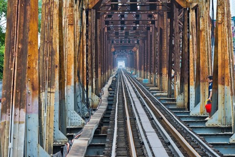 A Vietnamese State Railroad train crosses the Long Bien Railway Bridge across the Red River while a