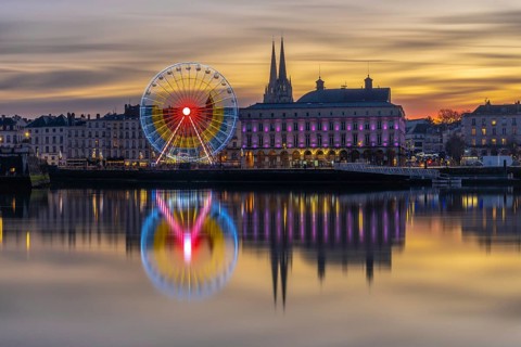 Bayonne cityscape illuminating the adour river at christmas, with a vibrant ferris wheel and