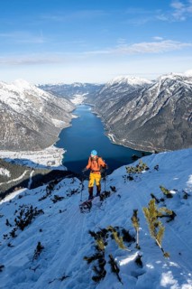 Picturesque view of Achensee and wintry mountain scenery, ski tourers climbing to Bärenkopf,