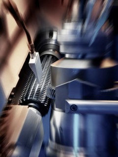 CNC controlled gear hobbing machine precisely machining a metal gear with cutting tool, flying