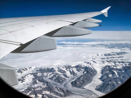 Window view from airplane, wing of an Airbus A380, ice-covered mountains and pristine glaciers of