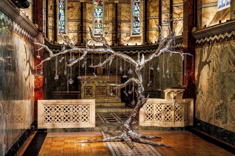Silver tree sculpture stands beneath stained glass in the marble chancel of Fitzrovia Chapel,