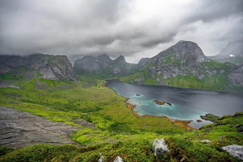 View over Kjerkfjorden fjord, mountain peaks and dramatic clouds, climb to Helvetestinden summit,
