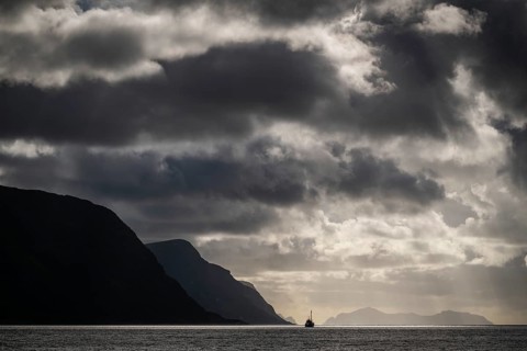 Dramatic lighting and dark clouds over the sea, island, ship, near Ålesund or Alesund, Møre og