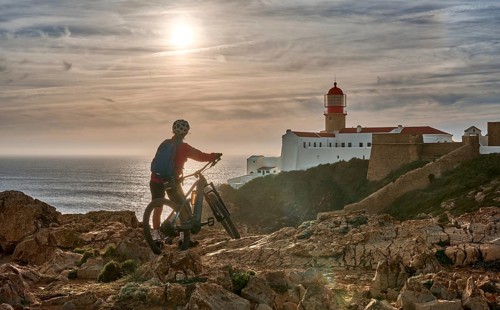Active senior woman cycling during moody golden hour near sunset at the the rock cliffs and