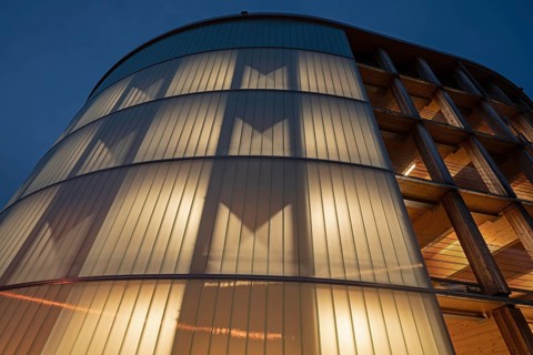 03.05.2026: Illuminated modern timber parking garage (Parkhaus am Bahnhof) with a curved wooden