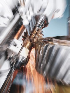 CNC controlled gear hobbing machine precisely machining a metal gear with cutting tool, flying