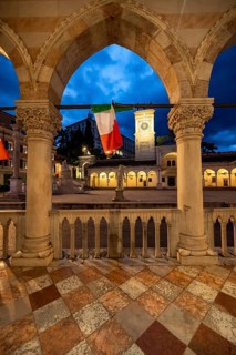 Arcades of the Loggia del Lionello with Italian flags, illuminated main square Piazza della Libertà