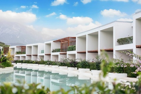 Modern white resort buildings hotel beside a tranquil pool, surrounded by greenery and under a blue