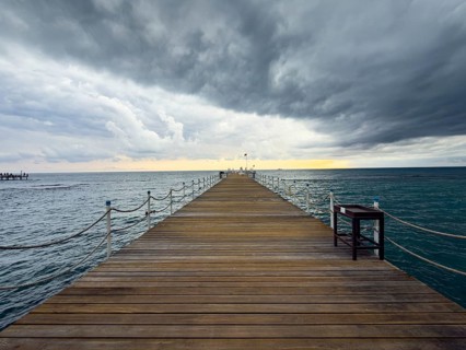 A wooden walkway leads into a stormy sea under a dramatic sky, Side, Manavgat, Antalya Province,