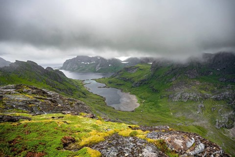 View over Bunesfjorden fjord, mountain peaks and dramatic clouds, climb to Helvetestinden summit,