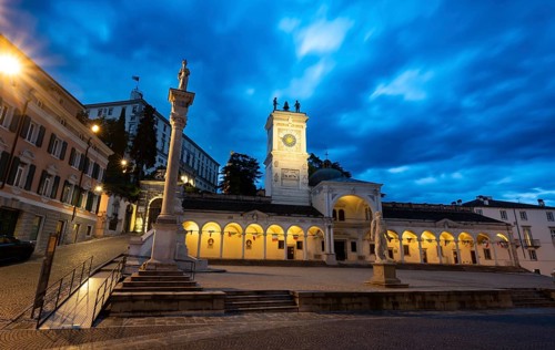 Illuminated main square Piazza della Libertà with Loggia e Tempietto di San Giovanni and clock