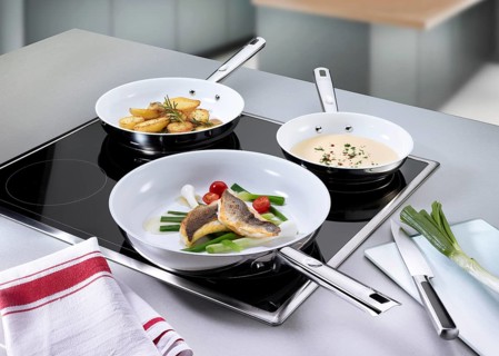 Hob with 3 pans including fish, potatoes and sauce, studio shot