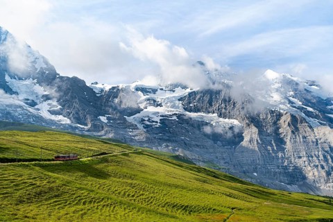 Jungfrau Railway to Jungfraujoch runs through green meadows, above the Kleine Scheidegg stop, rack