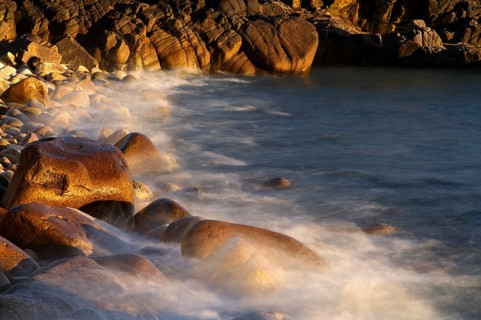 Stones, pebbles, pebbles, washed by water, waves, spray, motion effect, long exposure, evening