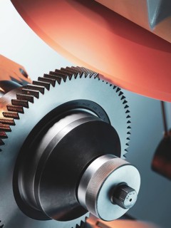 CNC controlled grinding machine precisely machining a metal gear with a rotating grinding wheel,