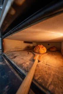 A bread is pushed into or removed from the oven with a wooden shovel, bake bread, Haselstaller Hof,