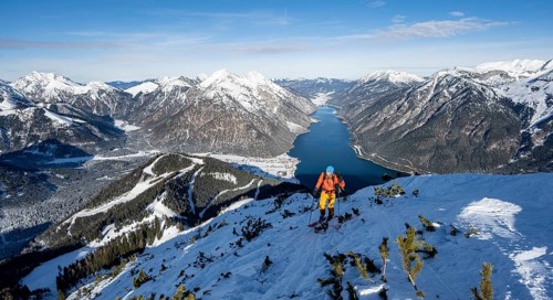Picturesque view of Achensee and wintry mountain scenery, ski tourers climbing to Bärenkopf,