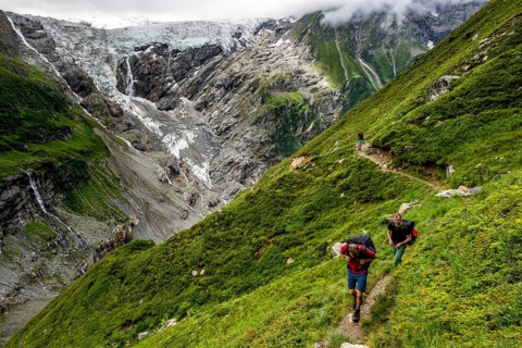 Mountaineers on a hiking trail, dramatic mountain landscape with Grindelwald-Fiescherfirn glacier,