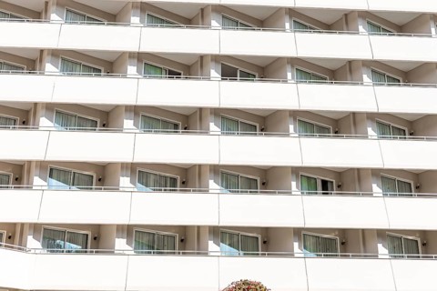 A modern hotel building with multiple balconies and large windows. The structure features a clean,