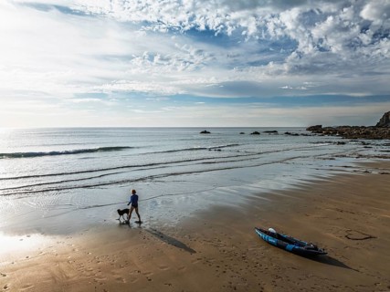Woman and dog with kayak on Beach from a drone, North Devon and Cornwall Coastpath Border from a